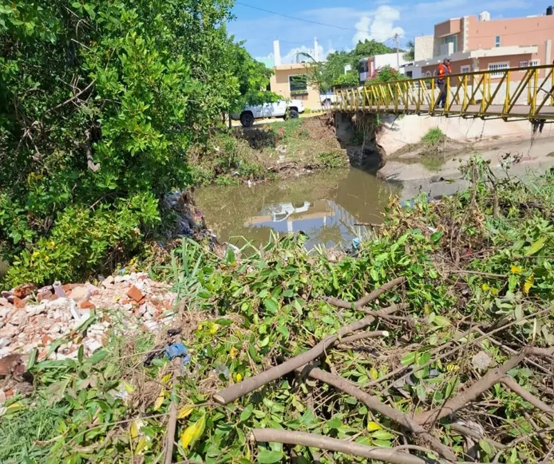 Escombros y basura acumulados junto al cauce del arroyo Jabalines, cerca de un puente peatonal